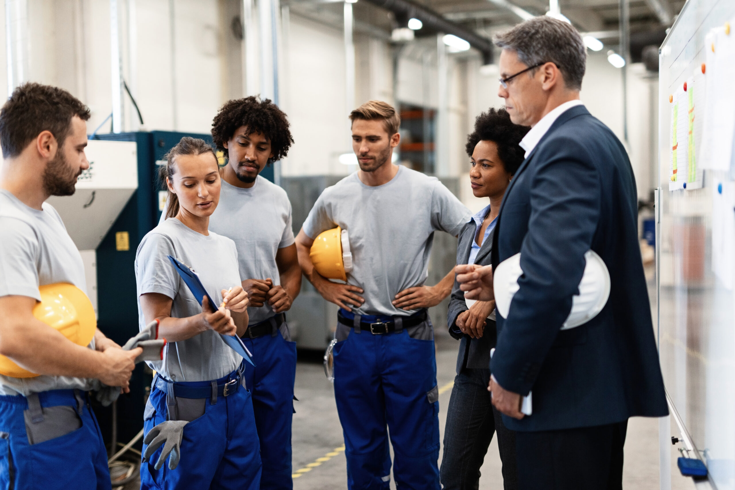 Female worker showing production reports to company managers in a factory.